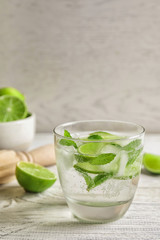 Refreshing beverage with mint and lime in glass on table