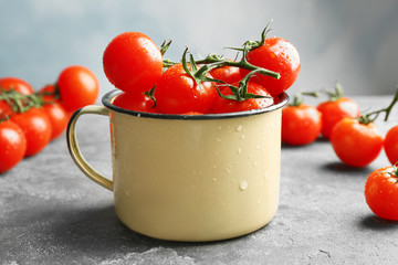 Metal mug with fresh ripe tomatoes on table