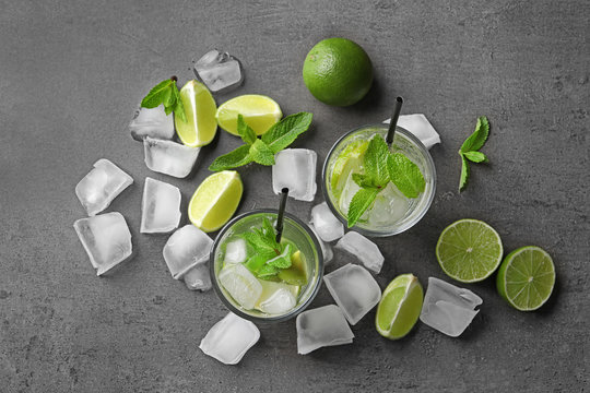 Flat lay composition with refreshing lime beverage and ingredients on grey background