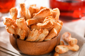 Puff pastry sticks cookies close-up in wooden bowl on table with  linen napkin
