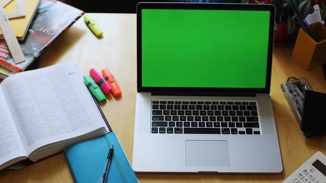 closeup top view of home office wooden table with chromakey laptop notebook computer empty green screen mock-up text business startup content digital technology office supplies at workplace nobody