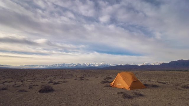 Time Lapse of Touristic Tent, Colorful Clouds in the Morning and Desert with Snowy Mountains on Background