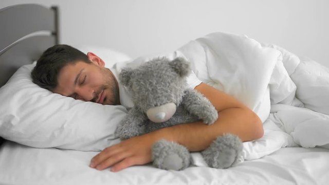 The man sleeping with a soft toy on the bed