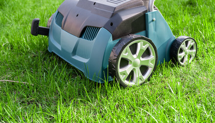 Fototapeta premium Scarifier on green grass. Work in the garden. scarifier