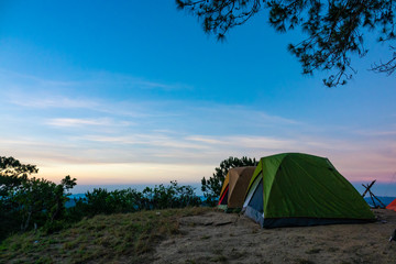 Outdoor camping vacation in the sunrise landscape. High-quality stock image of camping tent in the sunrise on mountain and forest. Adventures camping tourism and tent under pine forest