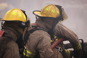 Fire fighters with fire hose putting out a blaze 