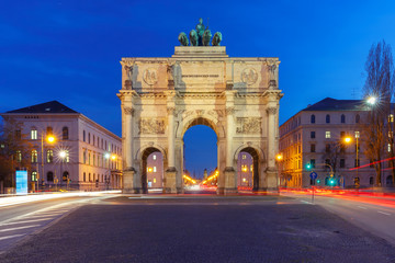 Fototapeta na wymiar The Siegestor or Victory Gate, triumphal arch crowned with a statue of Bavaria with a lion-quadriga, during evening blue hour in Munich, Germany