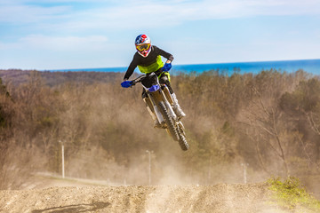 racer on a motorcycle in flight, jumps and takes off on a springboard against the sky.