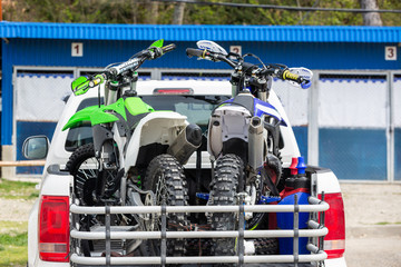 Fototapeta premium Rear viwe with two dirt bike motorcycles on the back of the truck with safety gear in residential setting.