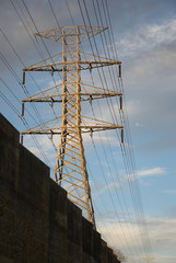 Electrical power line pylon isolated in the morning light against a blue cloudy sky 