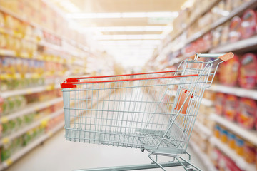 Supermarket aisle with empty shopping cart at grocery store retail business concept