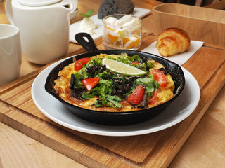 Classic Italian frittata with tomatoes and herbs in the pan