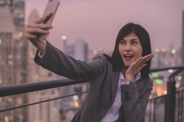 Business Concept. Asian businesswoman looking at mobile phone. Asian businesswoman happy at the top of the building. Beautiful young businesswoman Asians are happily playing mobile.