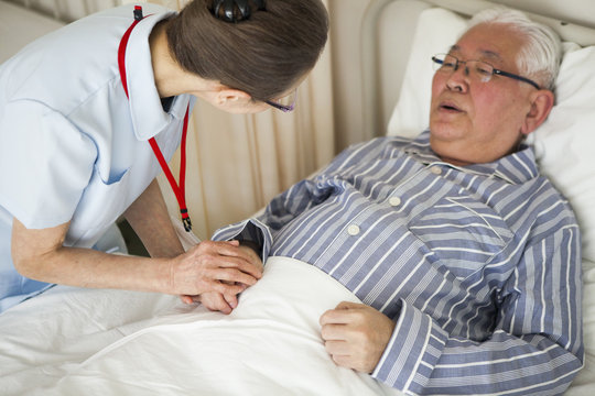 看護師が高齢者の患者の手を取り、励ましている。