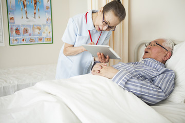 Obraz premium 看護師がタブレットを患者に見せて、説明をしている。