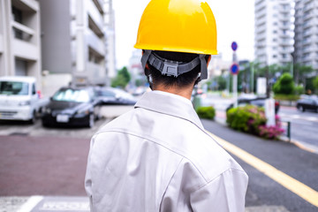 街を眺める作業着の男性