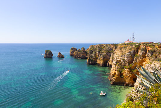 Panoramic overlook of Ponta de Piedade at Lagos, Portugal. Watersport activities in sea waters near the cliffs and caves.