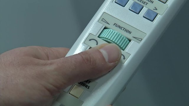 Close up of a hand holding the remote for medical equipment to rotate radiation machine