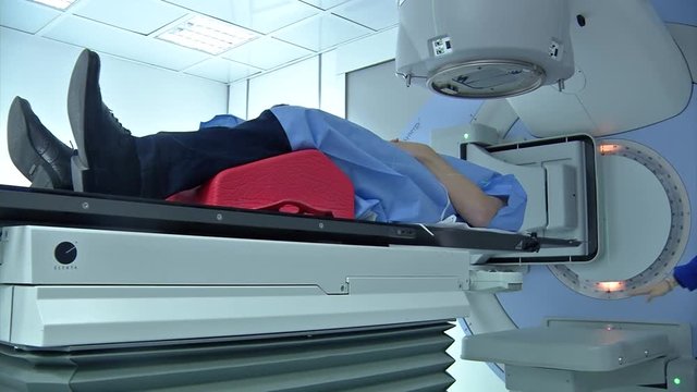 A patient lays on the cancer radiation linear accelerator table as doctors prepare him for treatment