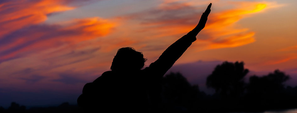 Panorama Of Silhouette Of A Man At Sunset With His Hands Up. Concept Of Victory