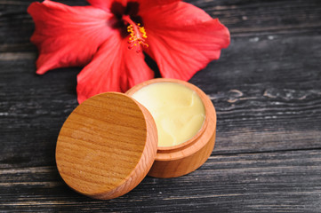 red flower and a jar of face cream on black boards