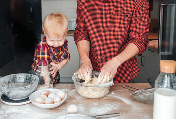Dad and son make dough in the kitchen