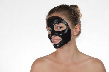 Happy beautiful girl smiling on a white background in a cosmetic mask black