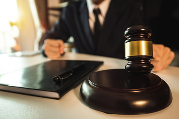 Justice and law concept.Male judge in a courtroom with the gavel,working with,digital tablet computer docking keyboard,eyeglasses,on wood table 