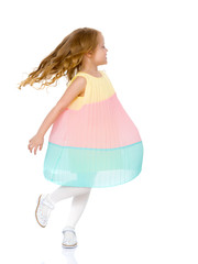 A little girl in a dress is spinning.