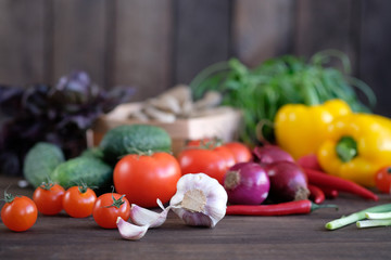 Vegetable.Fresh vegetables: tomatos, cucumbers,peppers,mushrooms,radishes ,onions, garlic and green seasonings on  old rustic oak table.