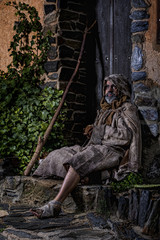Man, dressed in rags, begging through the streets of a village