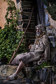 Man, dressed in rags, begging through the streets of a village