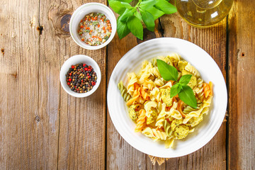 Pasta with slices of fried chicken fillet on an old wooden table.