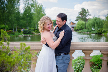 Romantic tenderness bride and groom at park. Young lady plus size enjoying moments in summer time. Beautiful bride posing with groom in her wedding day, pretty girl in a wedding dress 