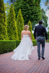 Romantic tenderness bride and groom at park. Young lady plus size enjoying moments in summer time. Beautiful bride posing with groom in her wedding day, pretty girl in a wedding dress 