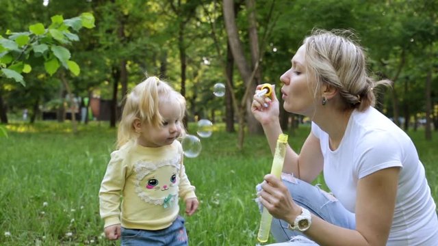 Woman and child playing with soap bubbles outdoors