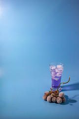 cocktail with grape on blue background vertical right position.