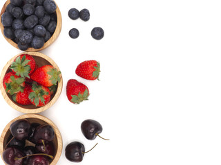 Fresh summer fruits, Cherry, strawberry, and blueberry in wooden bowl isolated on white background.
