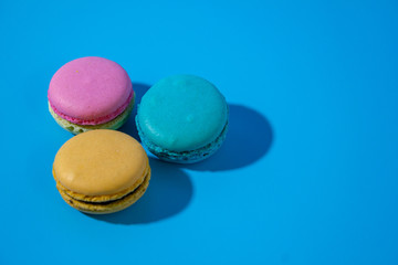 Macarons on cyan background top view left position.