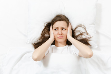 Top view of head of tired brunette young woman lying in bed with white sheet, pillow, blanket....