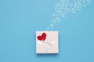 White gift box, red heart and Icon Question mark on a blue background. Minimalistic style. Concept surprise and suspense, a gift from a loved one. Flat lay, top view