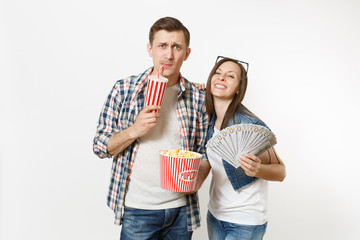 Young smiling couple, woman and man watching movie film on date holding bucket of popcorn plastic cup of soda or cola and bundle of dollars cash money isolated on white background. Emotions in cinema.