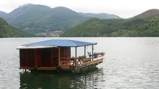 Wooden house floating on river landscape