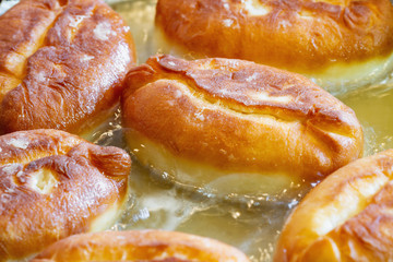 Homemade pies are deep-fried. Patties from yeast dough are fried in sunflower oil. Closeup, selective focus