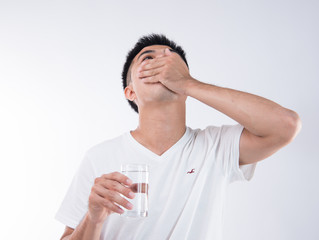 A man feels sick after eating too much delicious zongzi(rice dumpling) and is going to eat stomach medicine on Dragon Boat Festival, Asian traditional food, white background
