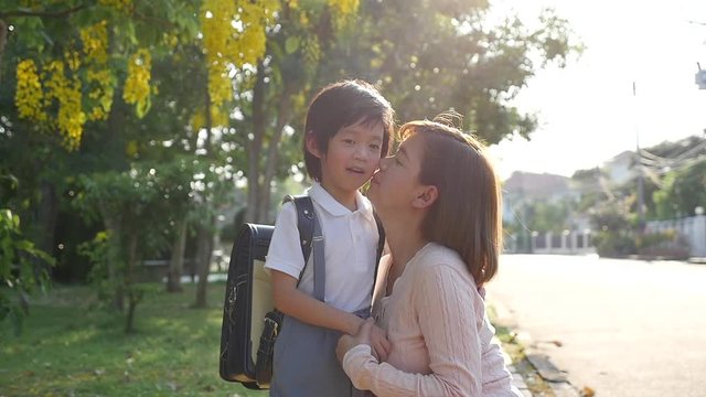 Asian mother  saying goodbye to her son as he leave for School,back to school concept 