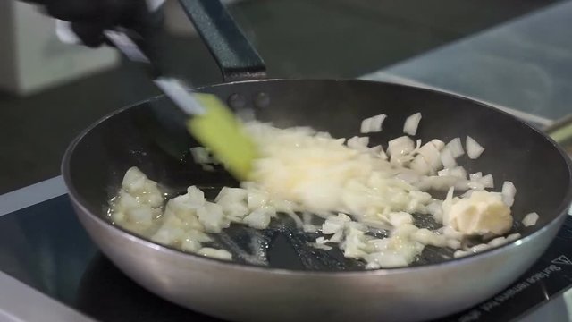 Cooking onions in a frying pan. Clip. Frying onions in a cast iron pan