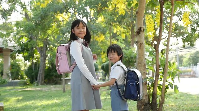 Cute Asian children going to the school outdoors 