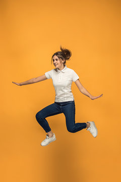 Freedom in moving. Pretty young woman jumping against orange background