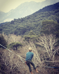Naklejka na ściany i meble Highliner on a rope. Highline on a background of mountains. Extreme sport on the nature. Balancing on the sling. Equilibrium at altitude.